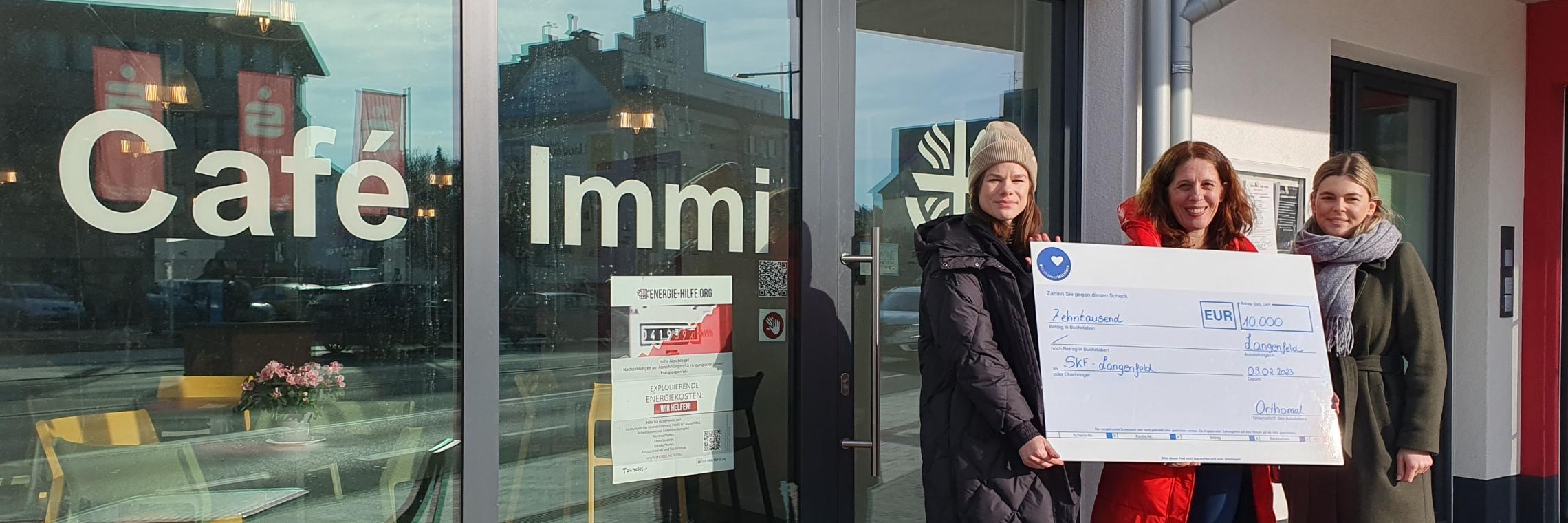 Kim Horeis (links) und Lisa Trapp (rechts), Mitarbeiterinnen von Orthomol, übergeben einen Spendenscheck an Stephanie Krone, Geschäftsführerin des SkF e.V. Langenfeld.